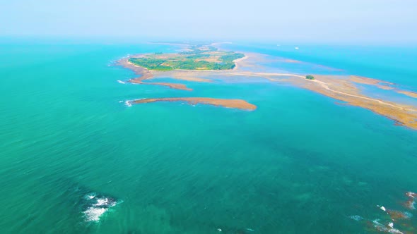 Tropical empty island surrounded by turquoise ocean. Daylight aerial overview alt