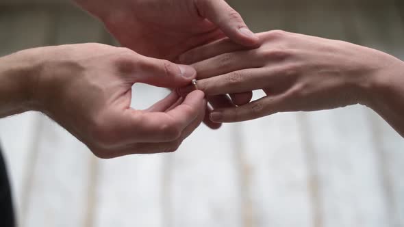 A man proposes to a woman and puts a ring on her finger alt
