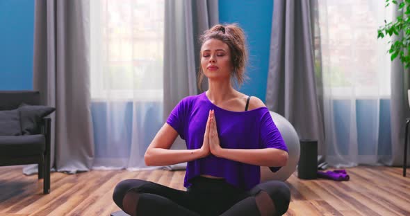 Portrait of Beautiful Young Woman Dressed in Fitness Clothes Meditates While Sitting in Lotus alt