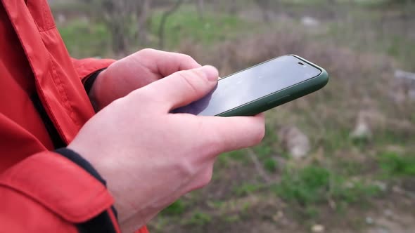 A Man Uses a Smartphone Surf the Internet on the Street