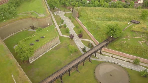 Aerial Establishing shot of Citadel Walls with walking bridge ,Trees and residential Estate visible alt