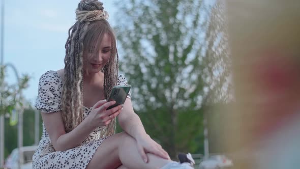 Young Beautiful Girl Writes a Message on a Smartphone