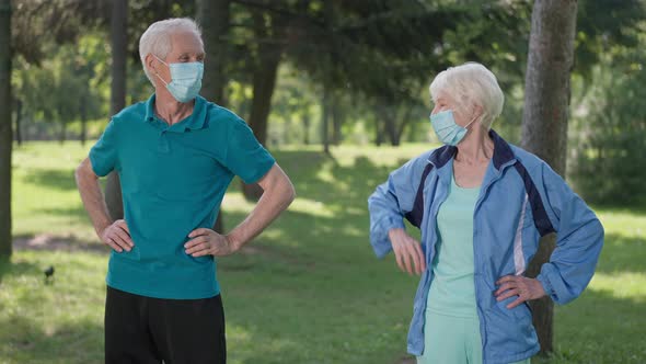 Joyful Senior Couple Training in Park in Coronavirus Face Masks Smiling Touching Elbows in Slow alt