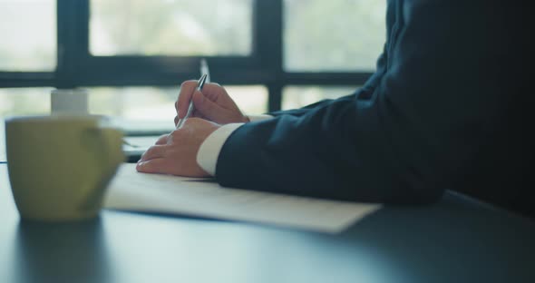 Close up of hands of businessman holding a pen and lie on the documents during a business meeting. alt