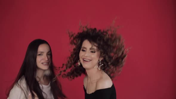 Two Happy Friends Dancing and Singing Against Red Background in Studio