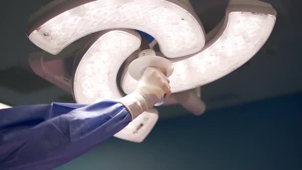 Surgeon hand adjusting light carefully in operating room during surgery, close-up. alt
