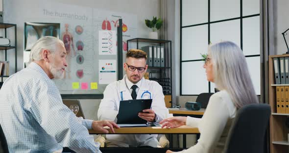 Senior Couple and Discussing their Health Complaints in Medical Office with Experienced Doctor alt