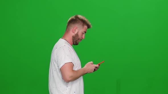 Portrait Bearded Guy Walking and Texting Message Vie Mobile Phone at Greenscreen. Chroma Key alt