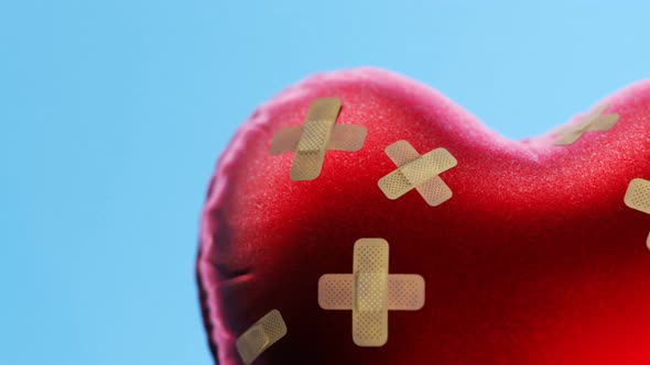 Red heart-shaped balloon fixed with bandaids. Broken heart concept. 4kHD alt