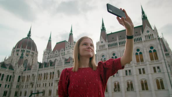 Tourist Woman Takes Selfie Photo or Film with Budapest Parliament Building