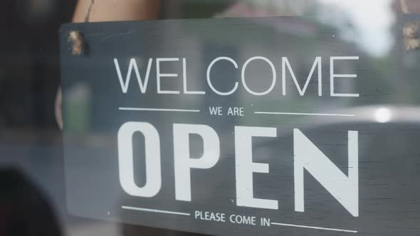 Young Asia girl wear face mask turning a sign from closed to open sign. alt