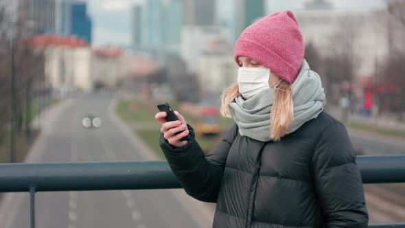Woman in Surgical Face Mask Uses Mobile App on Smartphone. Coronavirus Pandemic