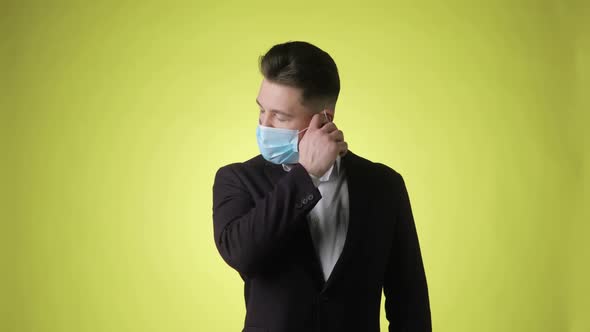 Bearded Man Takes Off Medical Mask and Makes Deep Breath on Yellow Background