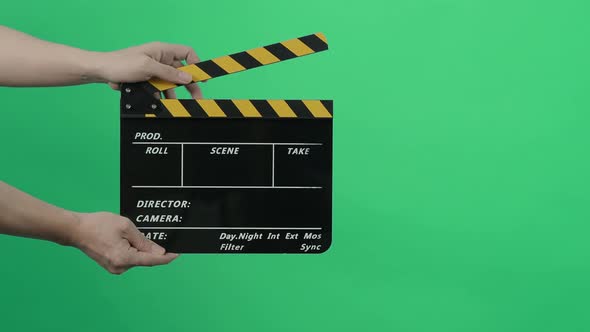 Film Slate or Movie Clapperboard with Blue Green screen background. Film crew man hold and hit