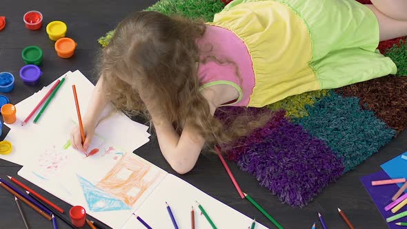 Young child lying on floor and drawing cute picture in illustration school alt