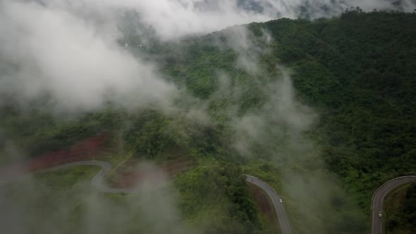 Aerial view flying above lush green tropical rain forest mountain with rain cloud cover during the r alt