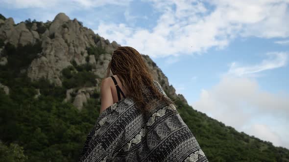 Girl with Afro Braids in a Light Cape Moves To the Top of the Mountain