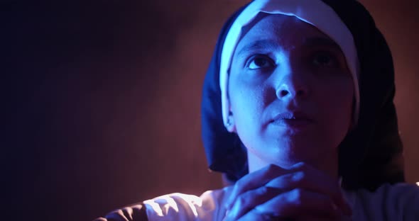 Nun Praying In The Dark In A Chuch Interior