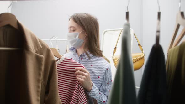 Woman with Covid Mask Looking for Dress in Clothing Retail Store or Fashion Showroom alt