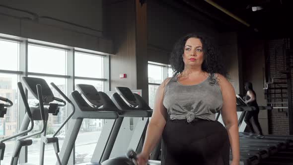 Beautiful Overweight Woman Exercising with Dumbbells at the Gym