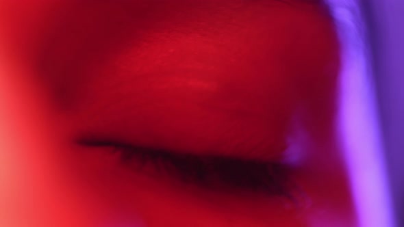 Female Model Pupil Dilation Under Bright Colorful Lights in the Studio. Close Up of a Woman Opening