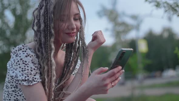 Young Beautiful Girl Writes a Message on a Smartphone