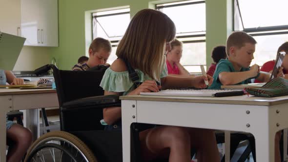 Physically challenged girl drawing in her notebook in the class alt