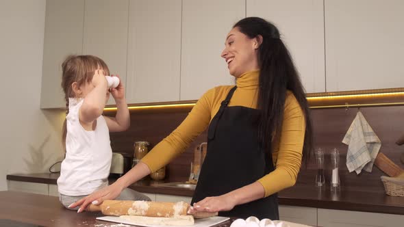 Cute Little Girl and Her Beautiful Mom Holding Eggs on Her Eyes and Smiling While Cooking in Kitchen alt