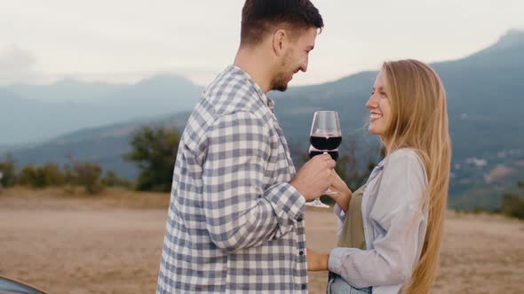 Young Couple Flirting and Tasting Wine at Countryside Against Mountains