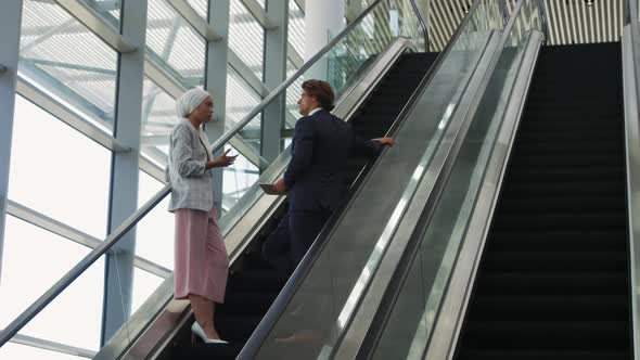 Young business people on an escalator in a modern building alt