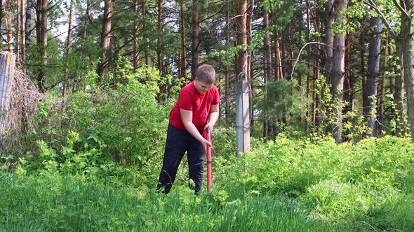 A Young Boy Mows Green Grass with an Electric Trimmer alt