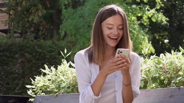 Cheerful young woman sitting in the city park.