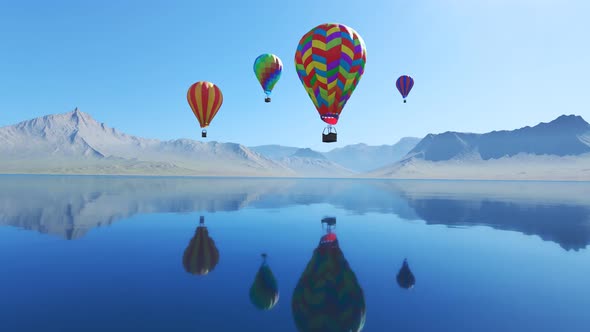 Multi-colored hot air balloons over the lake surrounded by mountains. Blue sky.
