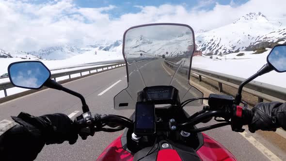 Motorcyclist Rides on Beautiful Landscape Snowy Mountain Road Near Switzerland Alps alt