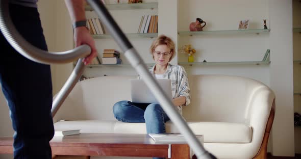 Tired Wife Sitting on the Couch Annoyed While a Noisy Little Daughter Screams Jumps on the Couch and alt