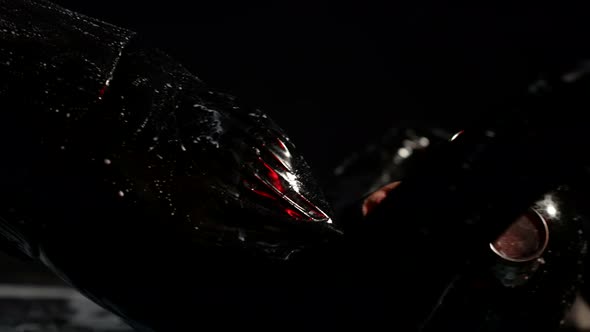 a Woman in a Black Latex Suit and Glasses is Lying on the Dark Floor alt