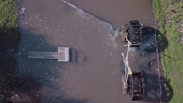 The Drone is Filmed Over the River on Which There is a Water Mill a Pier and a Boat