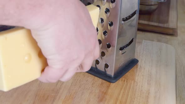 Medium Shot of Grating Emmental Cheese With a Box Cheese Grater alt