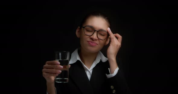 Female Office Employee Washes Down a Migraine Pill with Water From a Clear Glass