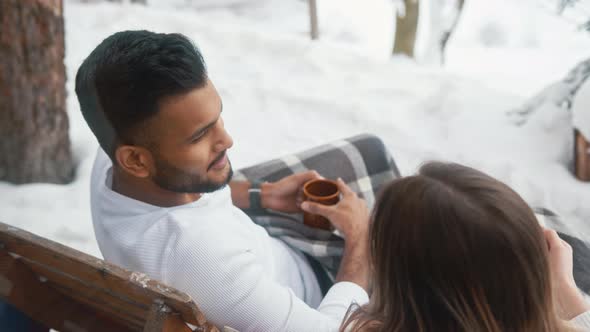 Happy Young Couple Drinking Hot Chocolate on the Balcony on Winter Day alt