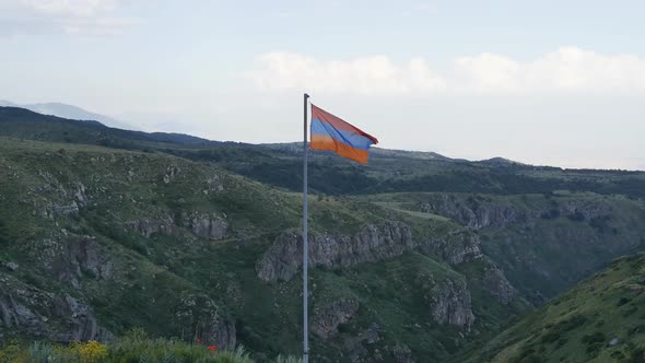 the Flag of the Republic of Armenia is Set in the Mountains Swaying in the Wind Against the Backdrop