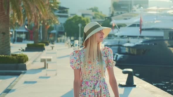 Blonde Woman in Elegant Summer Hat and Floral Dress Dreaming
