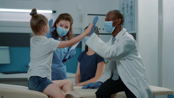 Medical Team Giving Highfive to Little Child After Successful Examination alt