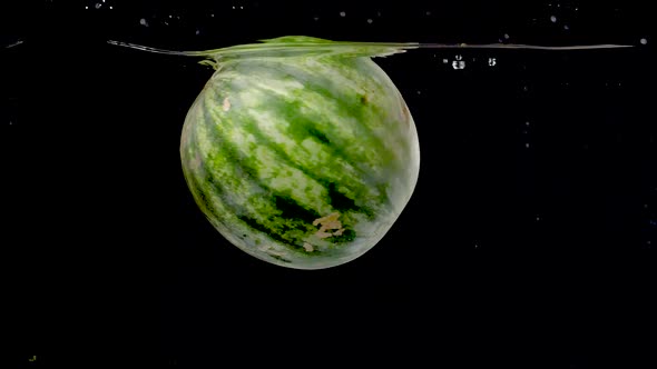 Colorful and vibrant watermelon being dropped into water in slow motion. alt