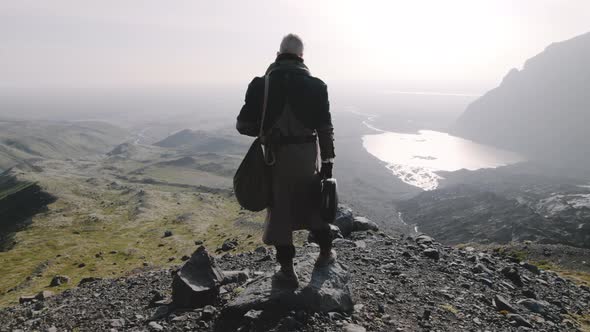 Lone Traveller Looking Down Into Sunlit Valley alt