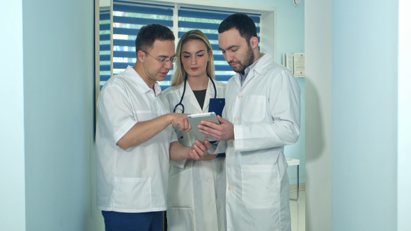 Male doctor showing something on tablet to his colleagues