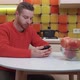 Young man sitting at the kitchen table with a phone in his hands - VideoHive Item for Sale