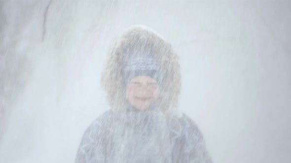 Portrait of a Beautiful Blonde Little Boy in the Winter Forest with Falling Snow