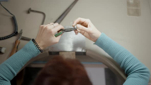 Topdown Of Jeweler With Pliers Is Working On Her Table alt