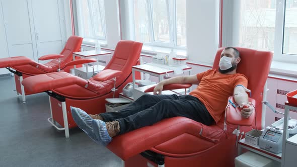 A Donor in a Mask Lies on a Couch. Man Donates Venous Blood. Blood Donation Concept alt